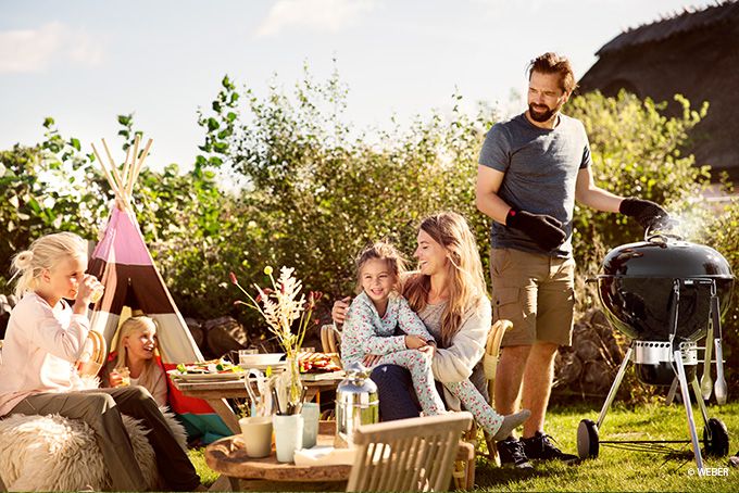 Familie mit 3 Töchtern grillt und spielt draußen im Garten