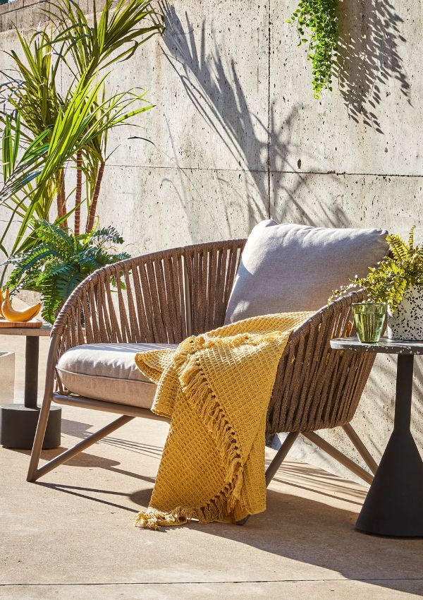 Rattan Sessel mit gelber Fransen-Decke